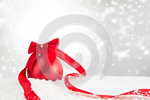 Red Christmas ball on a white snow surface over gray background