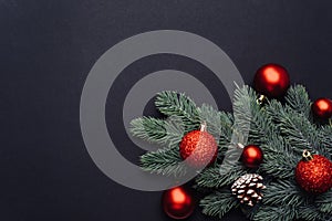 Red Christmas balls on a branch of a Christmas tree on a black background. Greeting card template, web banner mockup. Flat lay,