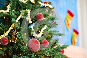 Red Christmas balls on a Christmas tree on a background of blue old doors in the New Year`s room decorated. Garland of popcorn. Ch