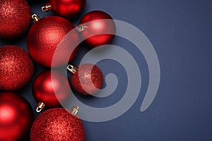 Red Christmas balls on dark blue background, top view. Space for text