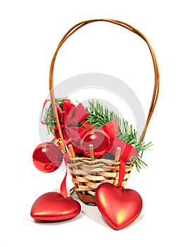 Red Christmas balls and hearts on a fur-trees branch in basket o