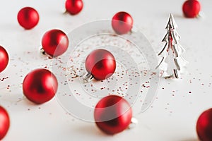 Red Christmas balls, small decorative Christmas tree and colorful glitters on white background