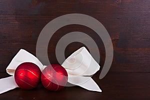 Red Christmas balls with withe ribbon on dark wooden background