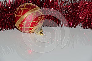 Red Christmas bauble and tinsel on white background