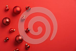 Red Christmas baubles decoration on red background. Flat lay, top view, copy space. New Year greeting card mockup, banner template