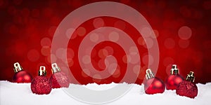 Red Christmas baubles on snow with a red background