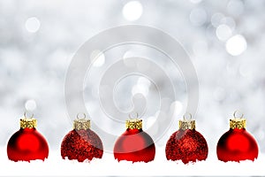 Red Christmas baubles in snow with silver background