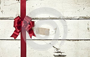 Red Christmas bow and ribbon on old painted white wood background