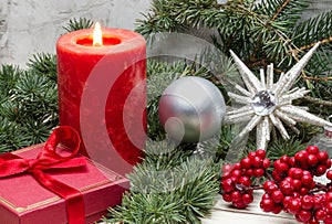 Red Christmas candle and Christmas gift box against wooden background