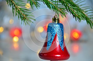 Red Christmas decor ball on green tree branch of a Christmas tree on a background of Christmas lights new year