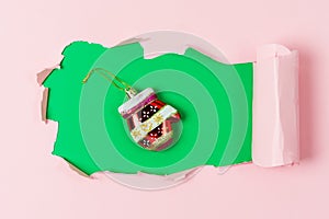 Red Christmas Decoration in Shape of Mitten Lying on Background with Hole Pink and Green Background