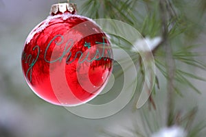 Red Christmas decoration on snow-covered pine tree outdoors