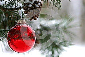 Red Christmas decoration on snow-covered pine tree outdoors