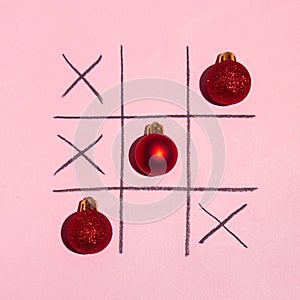 Red Christmas decoration tictac toe game on pink background. New year minimal creative idea.