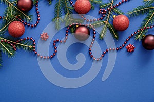 Red Christmas decorations, fir tree branches, Christmas balls on blue background. Christmas, winter, New Year concept. Flat lay,