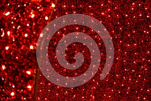 Red Christmas festive decorative background with tinsel, flashing lights. Wall illuminated by Christmas string rice lights bulbs.