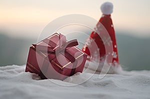 Red Christmas gift box and fir tree on snow. Christmas home decoration with snow and tree on blurred background at daytime with co