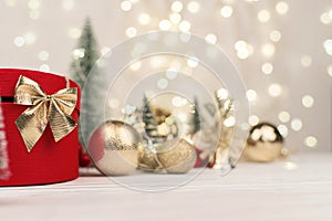 Red Christmas gift box with a gold bow on the background of bokeh, Christmas trees and toys