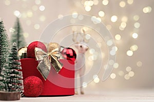 Red Christmas gift box with a gold bow and deer on the background of bokeh.