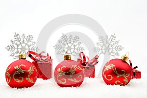 Red christmas gifts and baubles with snowflakes on snow