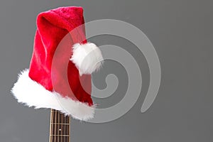 Red Christmas hat on guitar with grey background