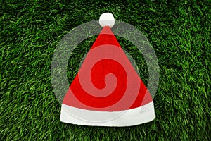 Red Christmas hat with space copy on green artificial grass background