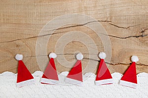 Red christmas hats on wooden background for a greeting card