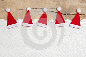 Red christmas hats on wooden background for a greeting card