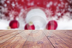 red christmas holiday background with empty wooden deck table over winter bokeh