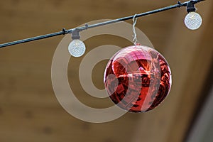 Red Christmas ornamental ball with reflection flanked by lights
