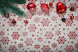 Red Christmas ornaments (cones,balls) and xmas tree on canvas background with red glitter snowflakes