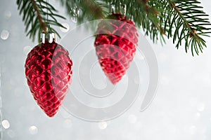 Red christmas ornaments cones on the xmas tree on glitter bokeh background. Merry christmas card.