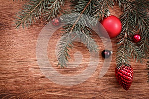 Red Christmas ornaments and fir tree branch on a rustic wooden background. Xmas card. Happy New Year. Top view