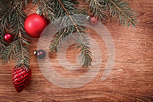 Red Christmas ornaments and fir tree branch on a rustic wooden background. Xmas card. Happy New Year. Top view