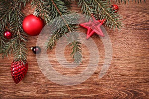 Red Christmas ornaments and fir tree branch on a rustic wooden background. Xmas card. Happy New Year. Top view