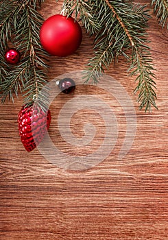 Red Christmas ornaments and fir tree branch on a rustic wooden background. Xmas card. Happy New Year. Top view