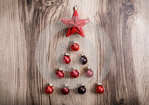 Red Christmas ornaments in the form of a Xmas tree on a rustic wooden background. Merry christmas card. Happy New Year