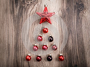 Red Christmas ornaments in the form of a Xmas tree on a rustic wooden background. Merry christmas card. Happy New Year. Top view