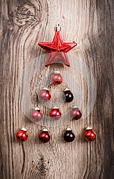 Red Christmas ornaments in the form of a Xmas tree on a rustic wooden background. Merry christmas card. Happy New Year. Top view