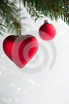 Red christmas ornaments heart and ball on the xmas tree on glitter bokeh background.