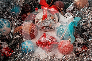 Red Christmas present stands on the snow against a background of a Christmas balls and shiny tinsel