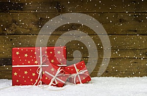 Red christmas presents on wooden background with snowflakes.