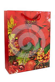 Red Christmas shopping bag made of paper decorated with green and red leaves, pine cones and Christmas balls on a white background