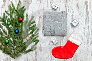 Red Christmas sock and a gray sweater. Decorated fir branch. Woo