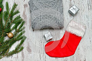 Red Christmas sock and a gray sweater. Decorated fir branch. Woo