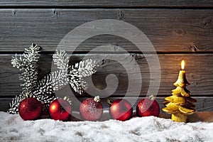 Red christmas spheres on pile of snow against wooden wall