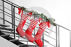 Red Christmas stockings with gift boxes hanging on stair railing, indoors.