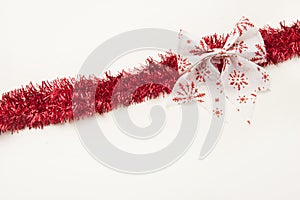 Red christmas tinsel with bow isolated on white background