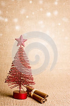Red Christmas tree, cinnamon sticks with copy space on orange Christmas background