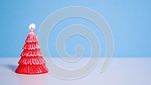 red Christmas tree wax candle burning on blue background. Slow motion full HD video. New Year or Christmas video banner